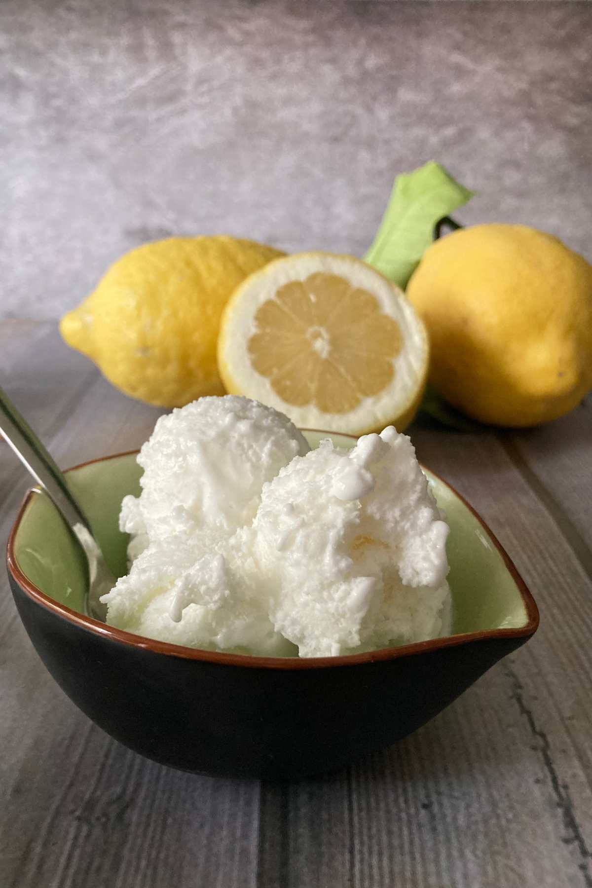creamy lemon gelato in a bowl with whole and sliced lemons