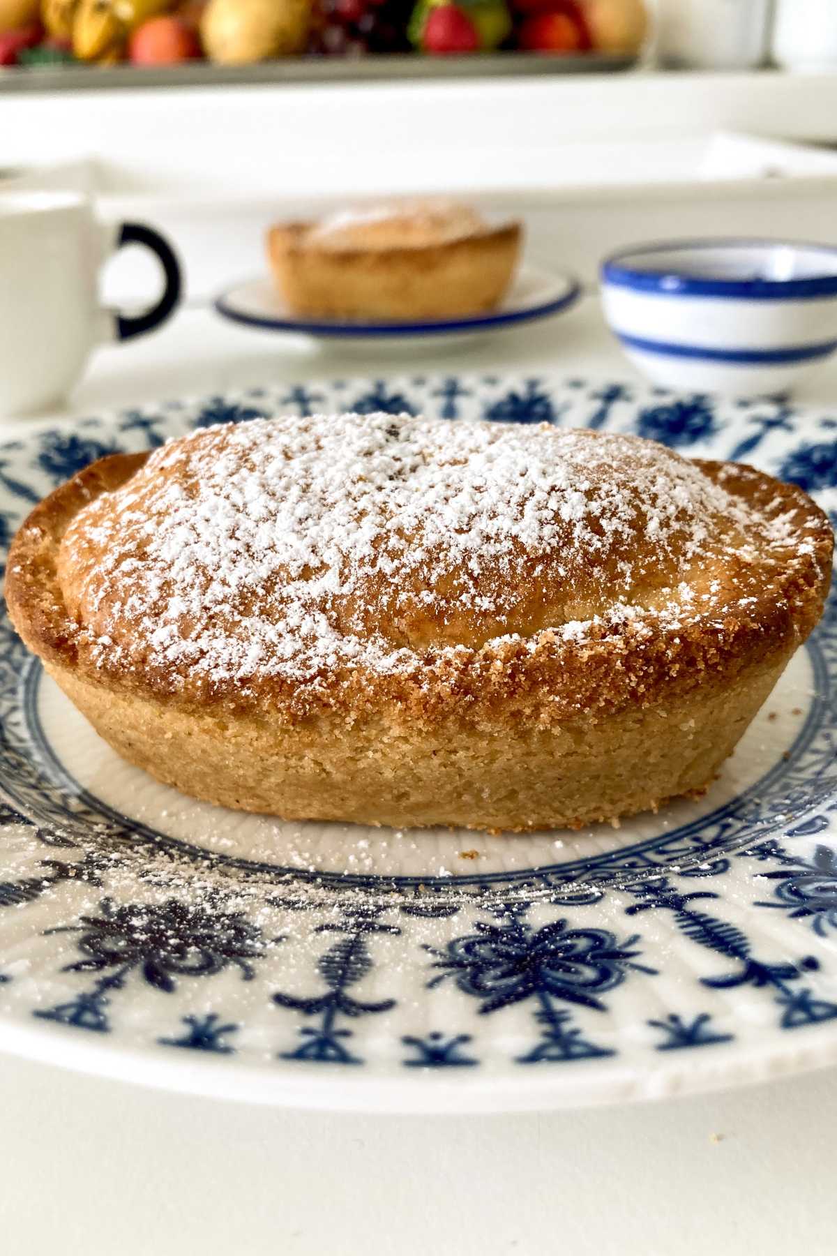 Whole pasticciotto leccese dusted with powdered sugar on a blue and white plate