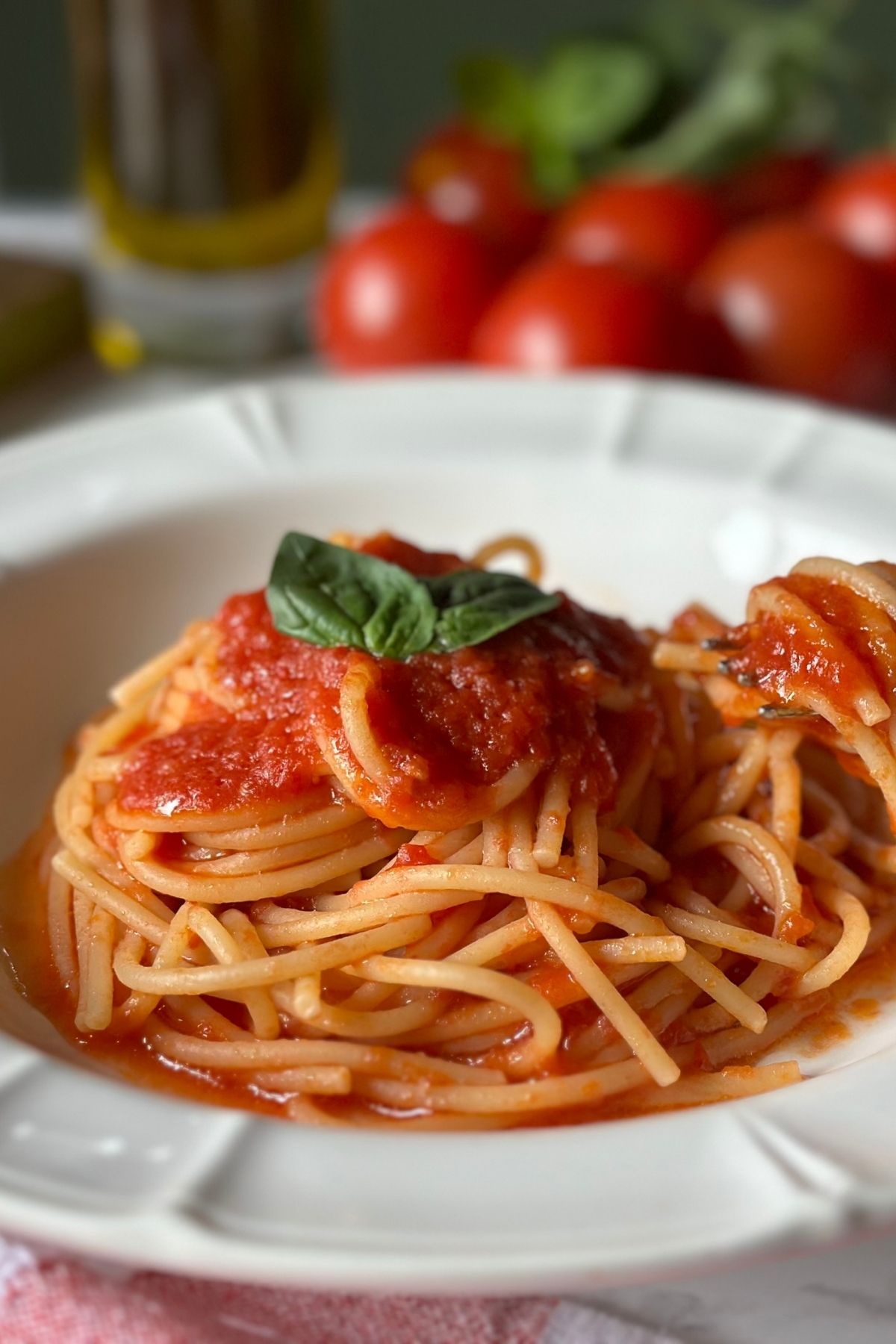 Close-up of spaghetti coated with tomato sauce and topped with fresh basil