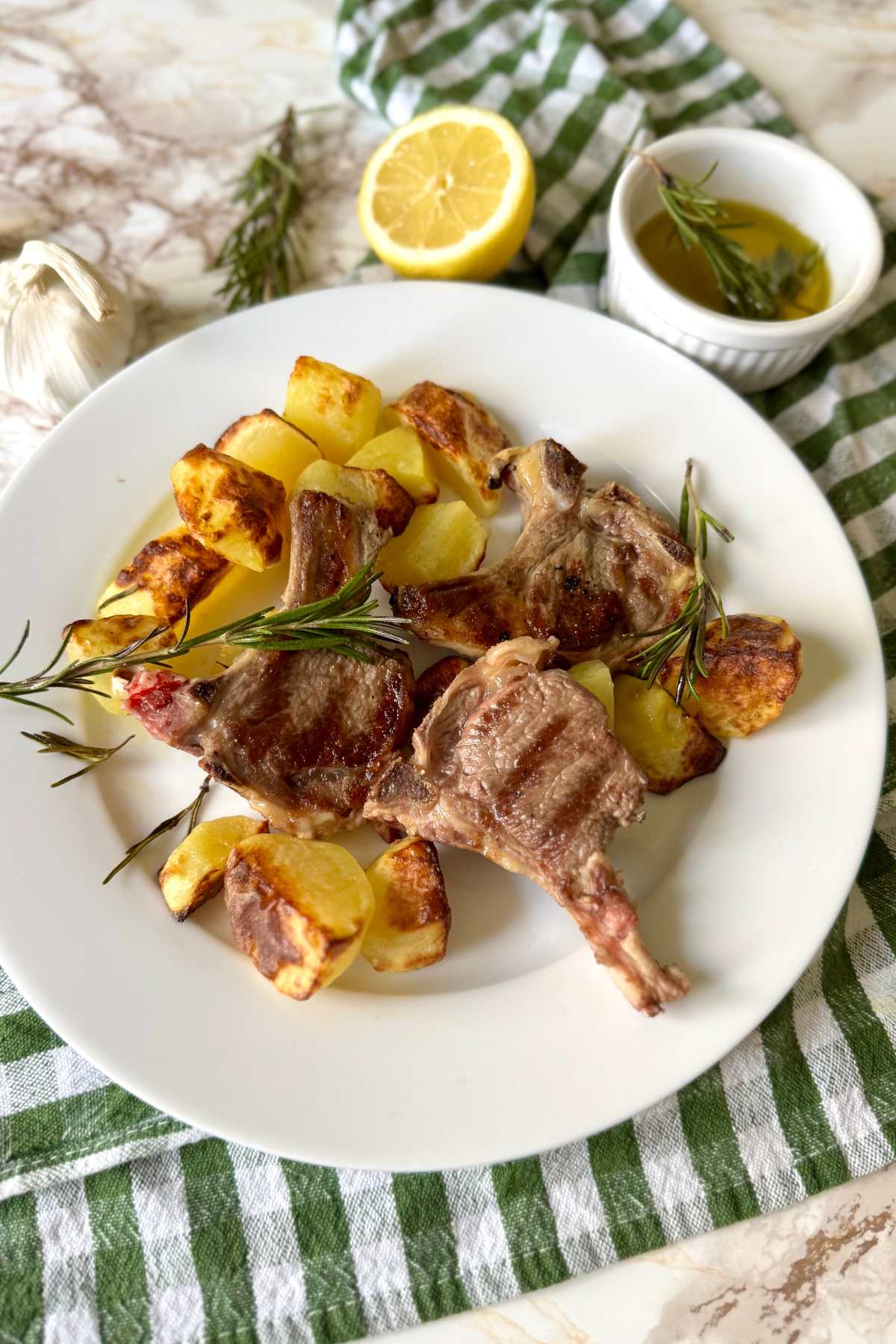 Abbacchio a scottadito served with roasted potatoes on a plate