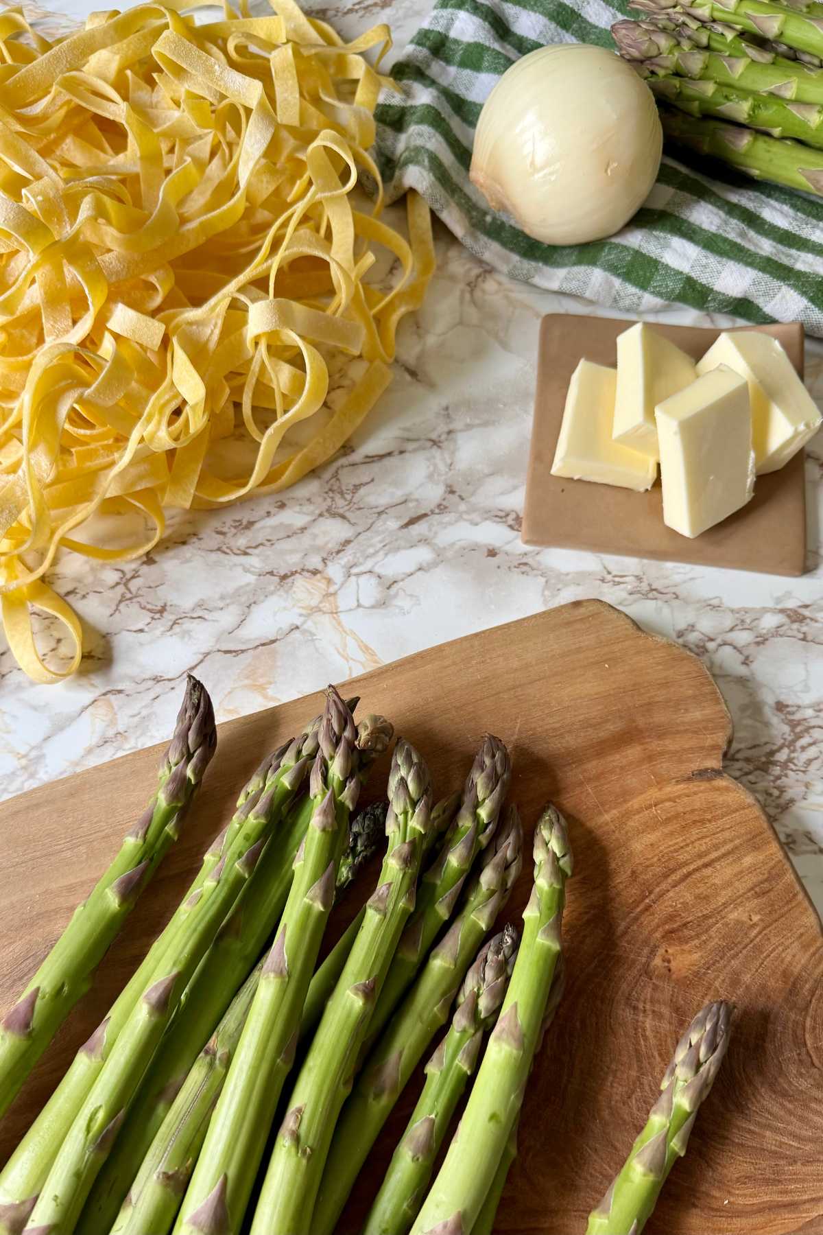 Fresh ingredients for asparagus pasta with tagliatelle, asparagus, butter and onion