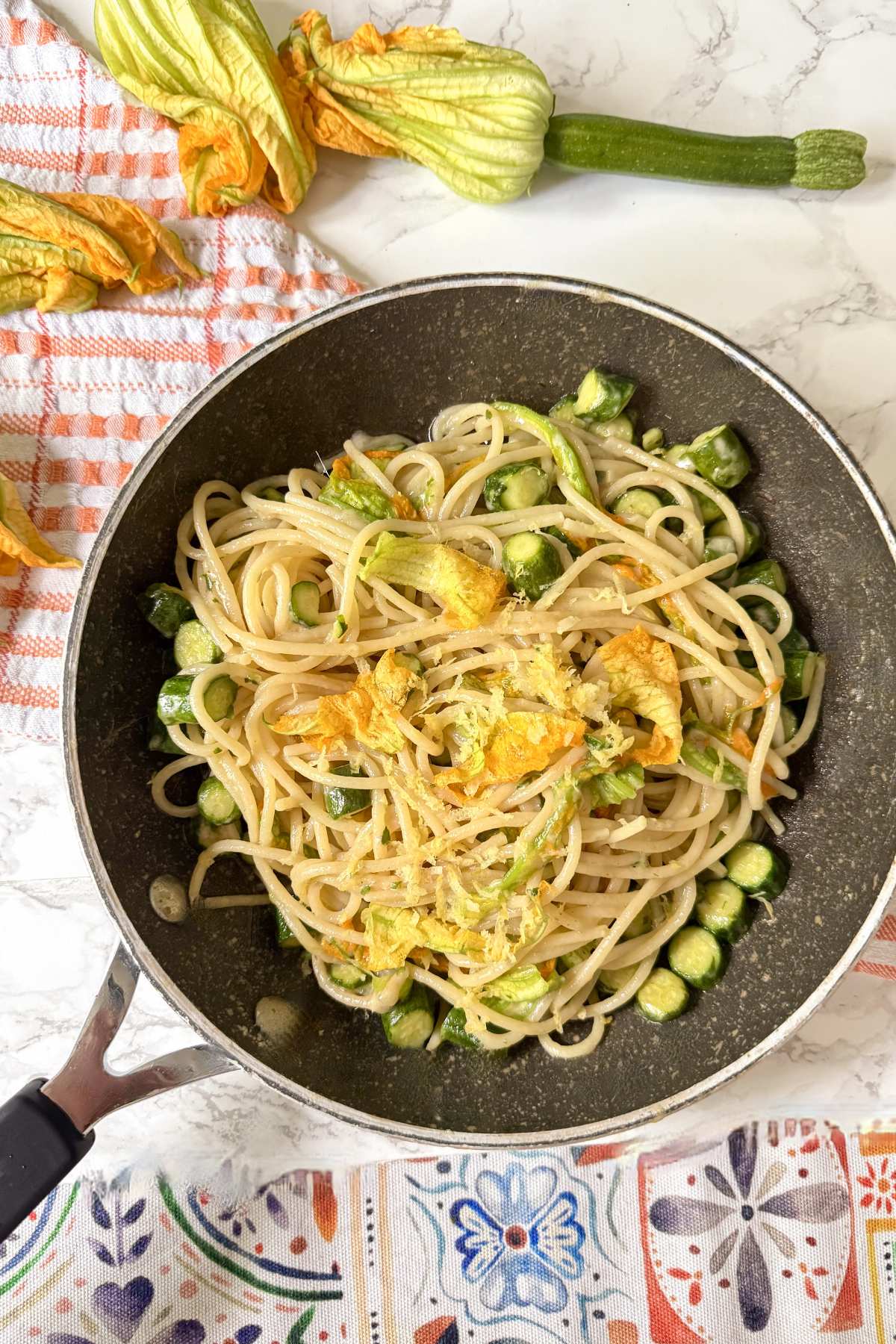 zucchini flower pasta in skillet with spaghetti, sautéed zucchini and fresh blossoms