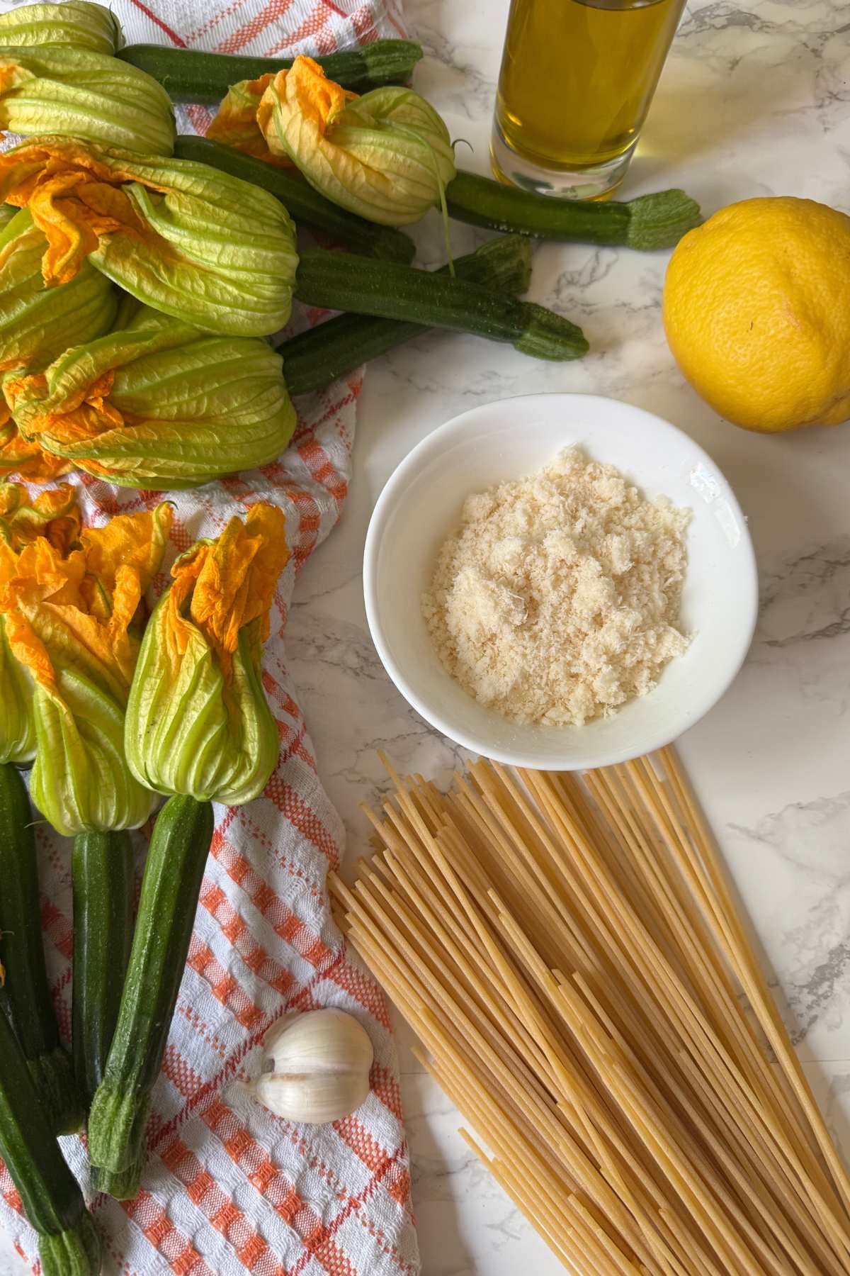 ingredients for zucchini flower pasta with fresh zucchini, blossoms, spaghetti and parmigiano reggiano