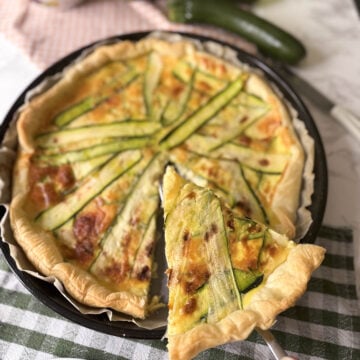 Zucchini and smoked scamorza pie with a slice served, made with puff pastry and fresh zucchini