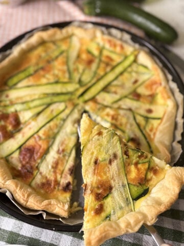 Zucchini and smoked scamorza pie with a slice served, made with puff pastry and fresh zucchini
