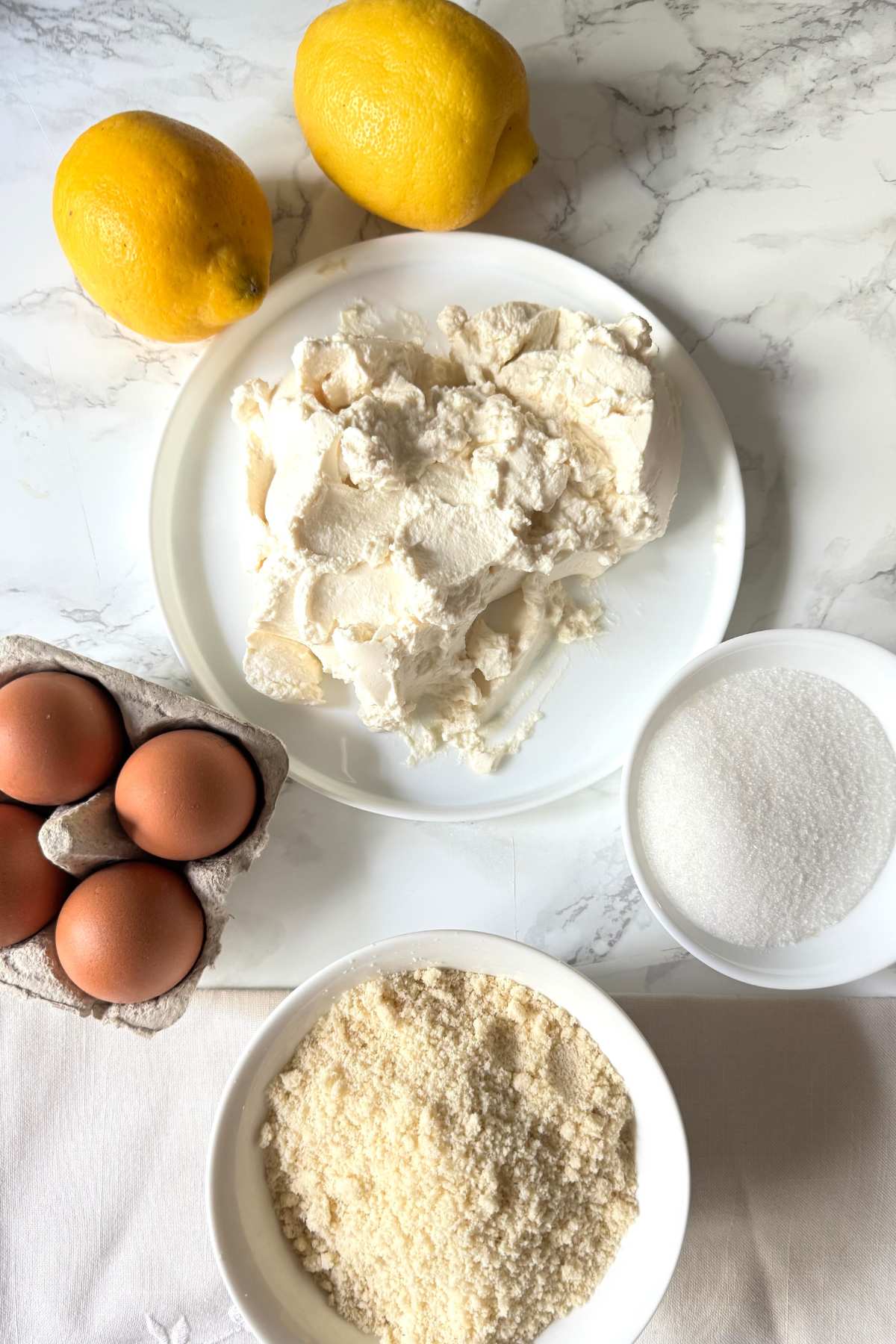 Ingredients for Italian almond and ricotta cake (torta delle monache) with ricotta, eggs, almond flour, sugar, and lemons