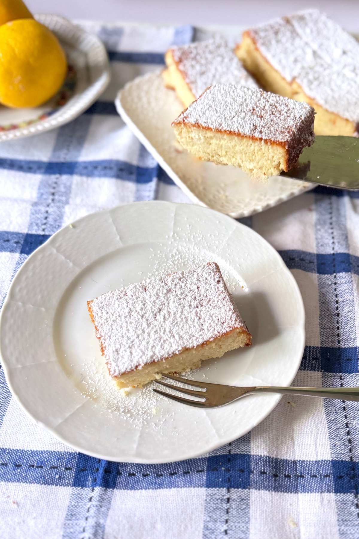 Serving Italian almond and ricotta cake cut into squares with powdered sugar