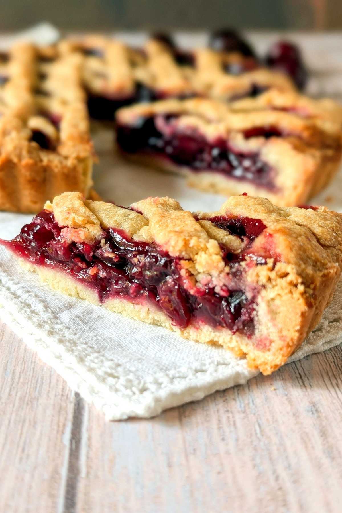 Slice of fresh cherry crostata with juicy cherry filling